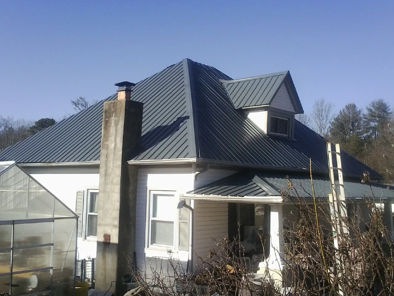 Dark blue standing seam metal roof on a white farmhouse with dormer — Slate & Tile Roof Repair by Roofing Brothers in Streetsboro