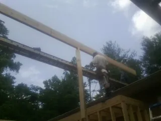 Carpenter setting a ridge beam over a new addition frame — Ice Dam Removal by Roofing Brothers in Streetsboro