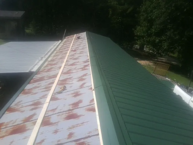 Old rusted panels beside newly installed green metal roofing — Wind Damage Roof Repair by Roofing Brothers in Streetsboro