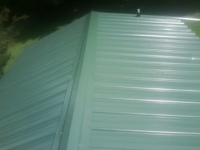 New green metal panels meeting at the ridge of a roof — Flat Roof Repair work by our crew in Streetsboro