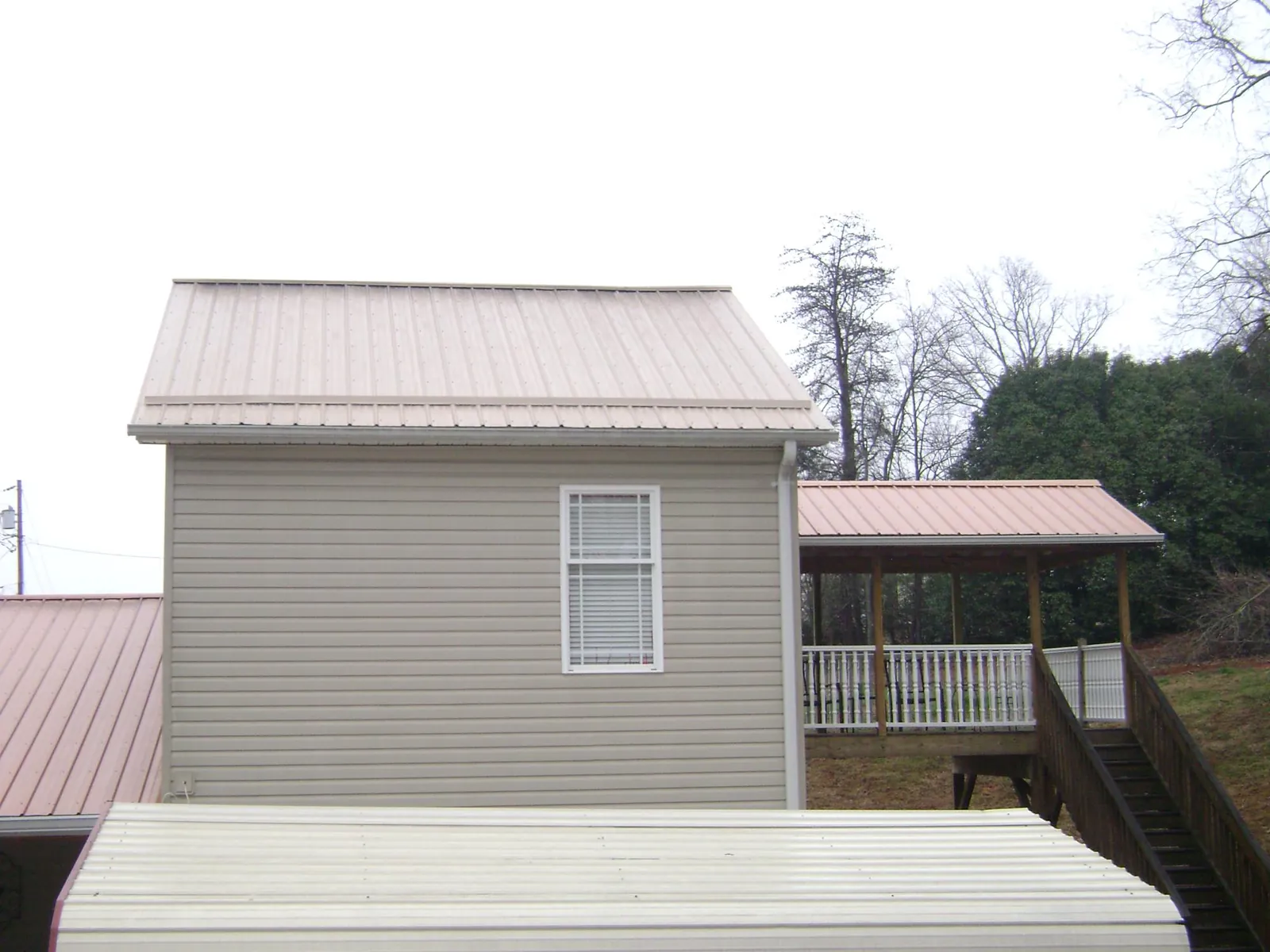 Tan metal roofs on a two story addition and attached porch, from a Roof Replacement job in Streetsboro