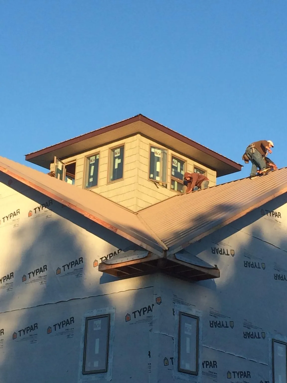 Roofers working around a rooftop cupola on a new metal roof at sunset — Roof Waterproofing in Streetsboro by Roofing Brothers